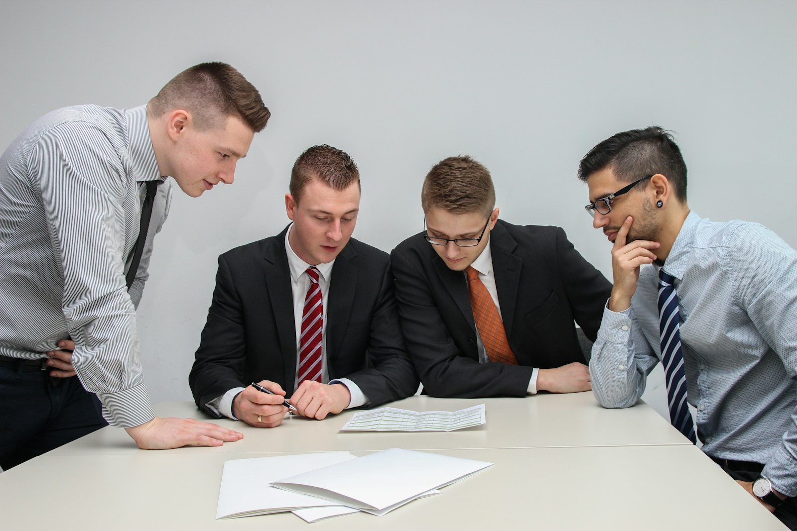 four men looking to the paper on table, business interruption
